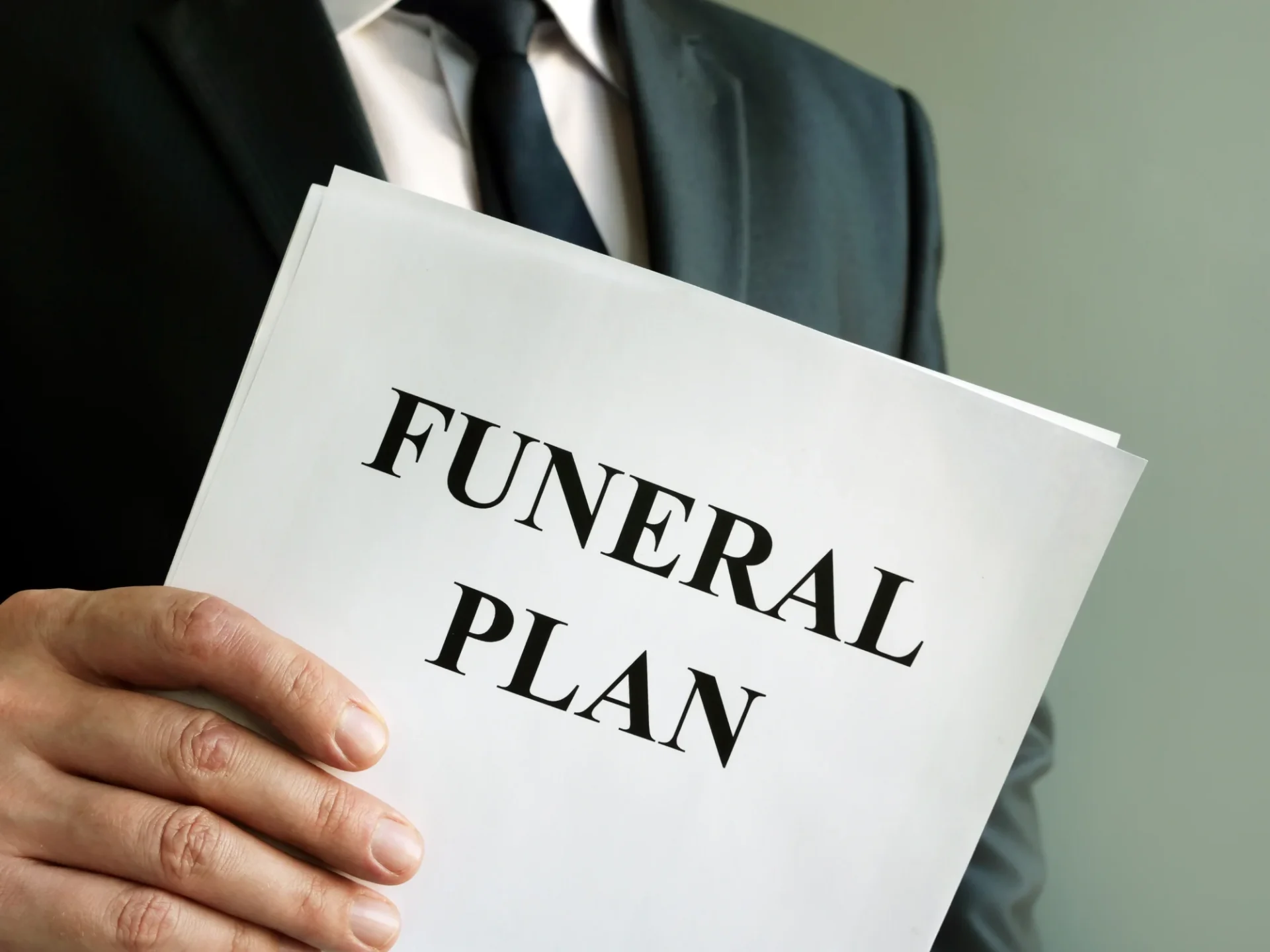 Person in a suit holding a document titled "Funeral Plan.