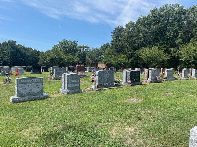 Graveyard with headstones and memorial flowers.